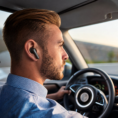 Man driving with wireless earbuds in, focused on the road